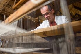 Tkadlec Josef Fidler ukazuje práci na tkalcovském stavu, 2023. Foto: Radek Pavlík